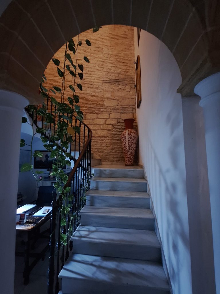 Escaleras de caracol en Hostal Fenix con pared de ladrillo vista y decoración minimalista.