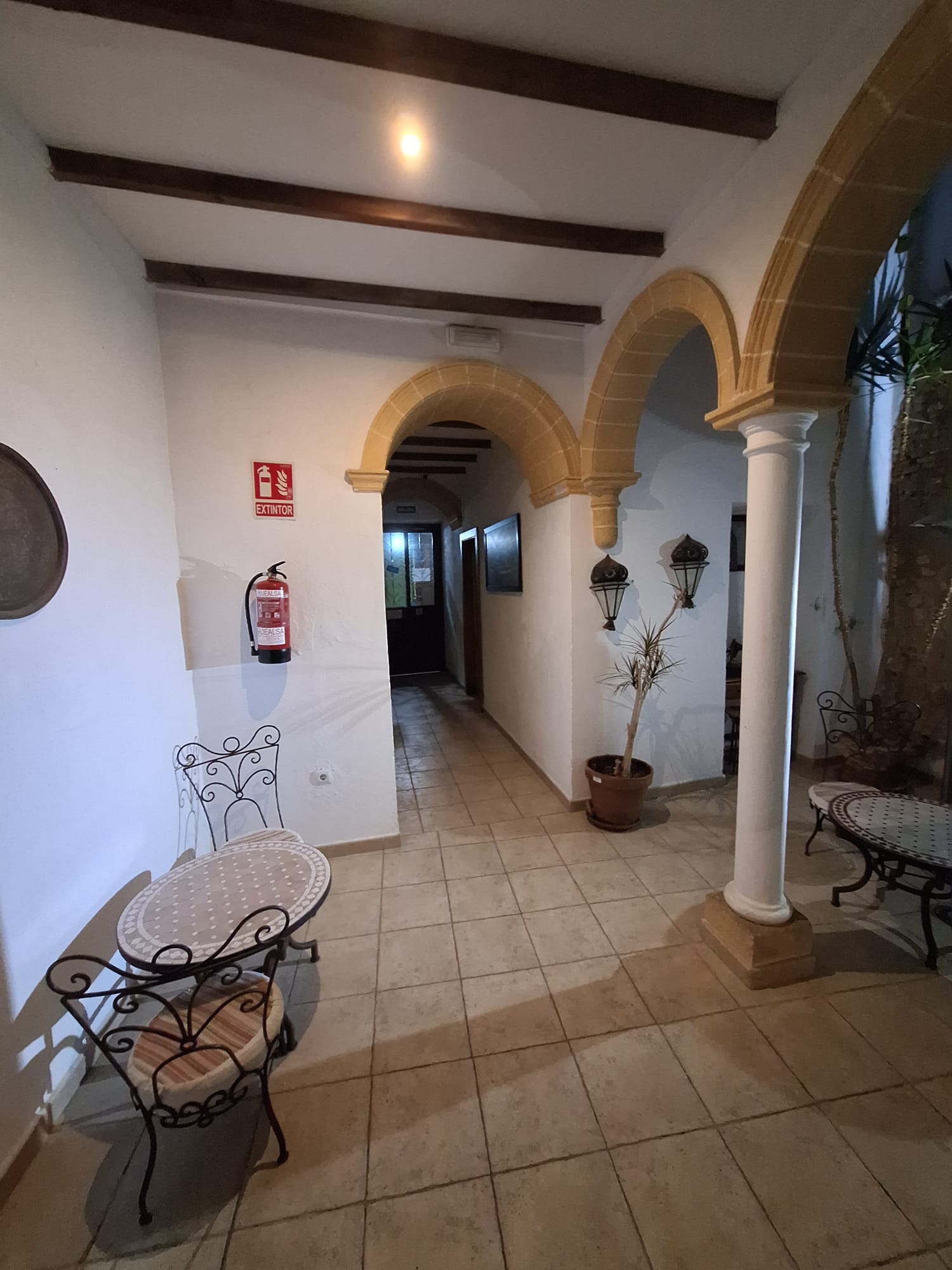 Rincón acogedor con arcos y mobiliario tradicional en Hostal Fenix durante la noche.